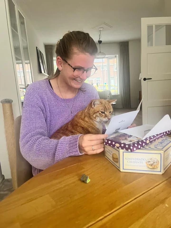 Een oppas met een rode kat op schoot die een kaartje leest