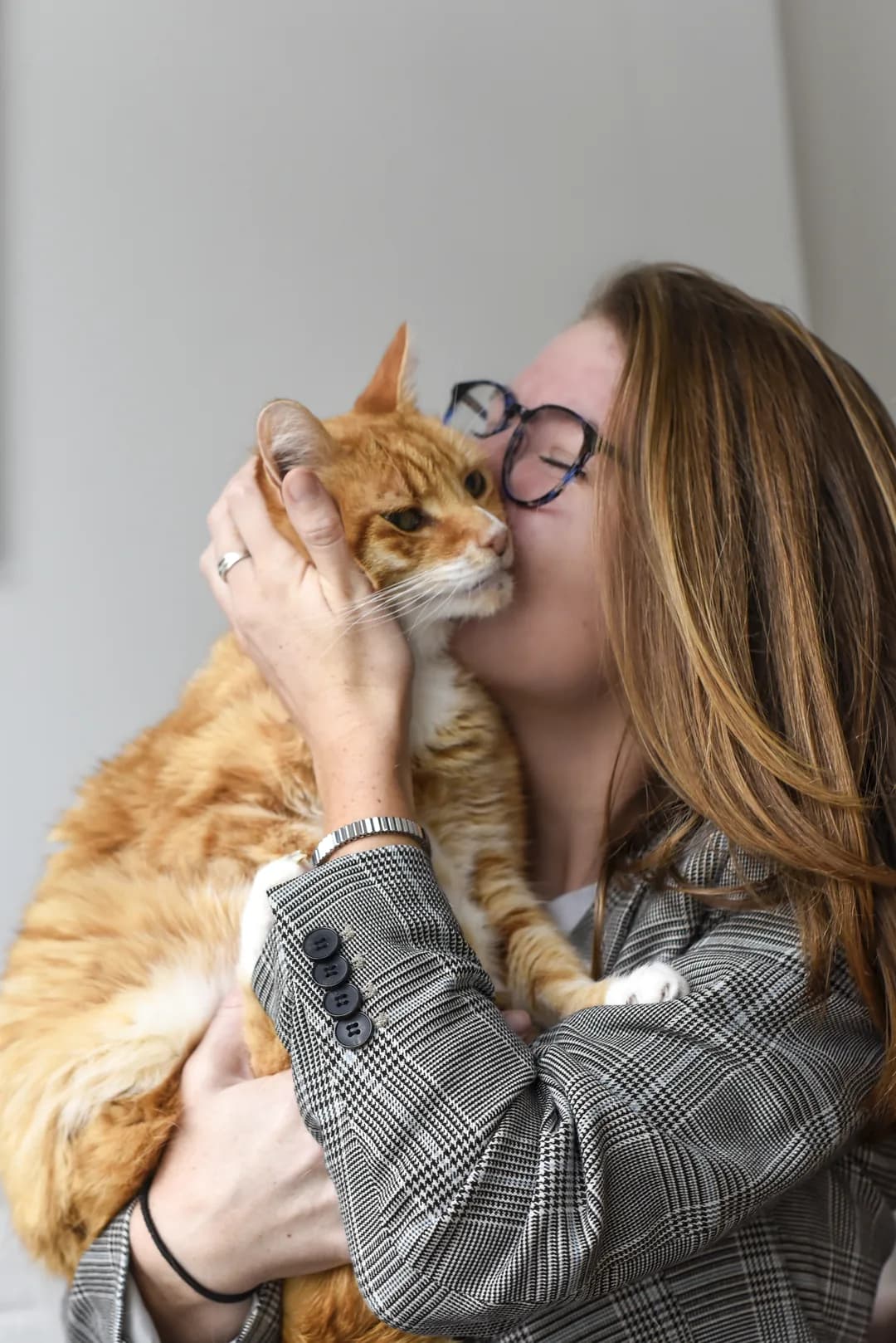 Een sitter knuffelt een rode kat, wang aan wang