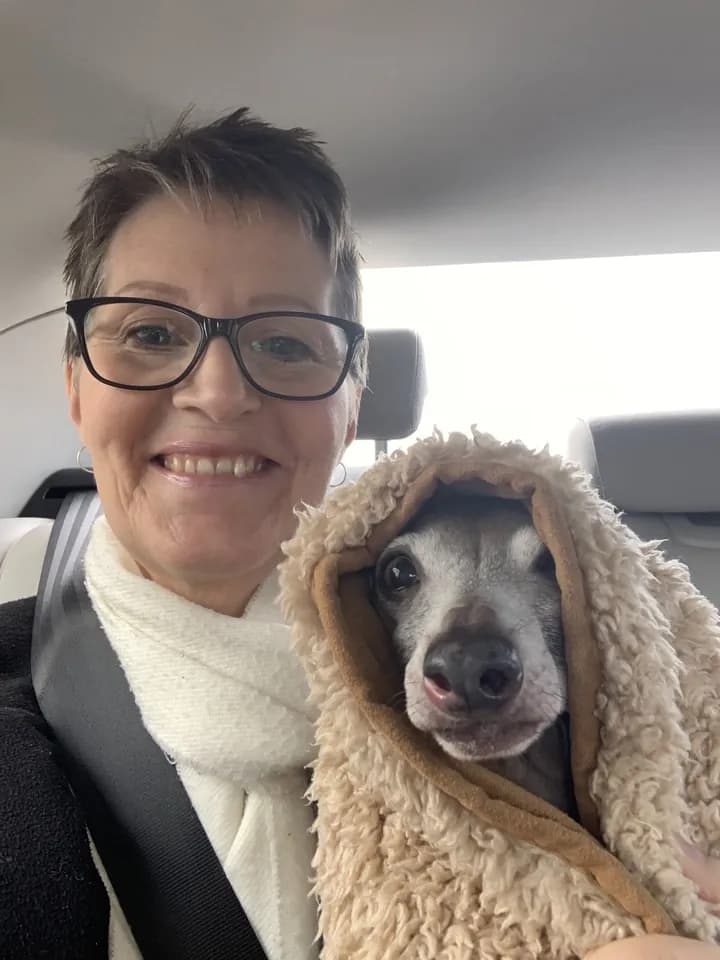 Een sitter in de auto met een klein hondje in een dekentje